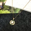 Detail view of the gold-tone titanium steel necklace with pearl and green zircon pendant. - Heavy Industry Wings Necklace