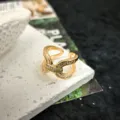Anello aperto dorato con zirconi scintillanti in un design a croce intrecciata chic e raffinato dettaglio. - Modello 4