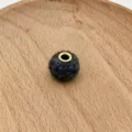 Close-up detail of dark grey wool felt bead with brass metal grommet center hole. - 15#
