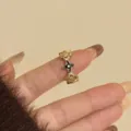 Gedetailleerde close-up van de prachtige gouden ring met zirkonia en bloemdesign. - C Zwart-3124
