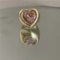 Gros plan détaillé d'une bague dorée épaisse ornée d'une grande pierre précieuse en cristal rose. - Anneau Doré Cœur Rose