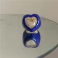 Gros plan détaillé de la bague cœur en émail bleu exagéré avec un grand cristal central. - Bleu