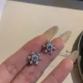 Close-up detail of sparkling snowflake stud earrings with blue stones and pearls. - Blue Rhinestone Pearl Snowflake (Style 2)
