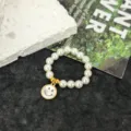 Close-up detail of a charming elastic pearl ring featuring a cute metal smiley face pendant. - Smile Face Pearl Elastic Rope Ring