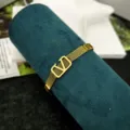Primo piano di un bracciale in maglia di acciaio inossidabile dorato con logo a V. - Braccialetto a Rete con Lettera V / Oro