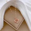 Dettaglio collana cuore in oro rosa, con ciondolo ad ali scintillanti e pietra centrale mobile. - Catena a forma di labbra / Oro rosa