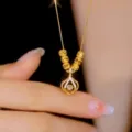 Primo piano dettagliato di una collana con ciondolo dorato, perle di metallo e pietra. - Oro - Collana Sacchetto Perline Liufu