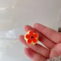 Close-up detail van vintage vijfbladige bloemring met sprankelend kristal en oliedruppel. - Oranje Bloem