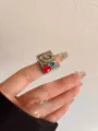 Close-up van brede vintage open metalen ring met sierlijke lijst, paarse kristal en rode hart. - Vintage Gesneden Ovale Paarse Edelsteen Stijl