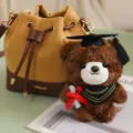 Schattige afstudeer beer pluche sleutelhanger pop met stijlvolle emmer tas accessoire. - Bandana Stijl / Dark brown bear