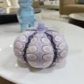 Vue detaillee de la peluche citrouille violette avec des motifs circulaires uniques sur la table. - Style à Pois Violets