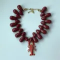 Gedetailleerd overzicht van de rode acryl kralenketting met een unieke kreeft hanger details. - Bordeauxrood