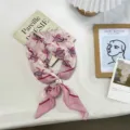 Detail view of pink retro paisley printed small scarf featuring elegant pearl accessory. - One Size / Pink
