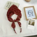 Detailed view of red floral pleated triangle scarf with cute wooden bead ends for spring styling. - 100*32cm / Brick Red