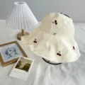 Gros plan détaillé du chapeau bob à carreaux beige avec de doux motifs de cerises brodées. - Taille unique / Jaune
