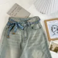 Detailed close-up of light wash denim jeans with a chic blue paisley print ribbon and bead belt. - Haze Blue Style (09#)