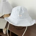 Detail view of a blue and white checkered bucket hat with chin strings and a small label. - One Size / Blue