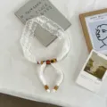 Vista dettagliata di un'elegante collana di pizzo bianco con perle color ambra stilose. - Stile Rosa