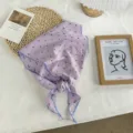 Close-up detail of a purple polka dot triangular silk scarf with blue trim for women neck wear. - Extended / Purple