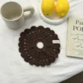 Gros plan détaillé de l'écharpe ou chouchou marron foncé en crochet au motif ajouré. - Brun