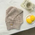 Closeup detail view of the stylish speckled knit balaclava hooded scarf with toggle buttons. - Oatmeal