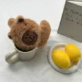 Detailaufnahme von süßen braunen Kapibara Plüsch Ohrenschützern in weißem Becher, schöne Deko. - Kaffee-Capybara Stil / Braunes Capybara