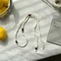 Gedetailleerd overzicht van een witte gebreide kralen ketting met kleurrijke accenten, retro. - 140*0.5cm / Wit