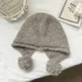 Detailed view of the cozy wool-blend balaclava with cute pom-pom earflaps and soft texture. - One Size / Gray