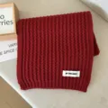 Detail shot of a cozy red knit scarf neatly folded, soft winter warm short neckerchief. - Burgundy