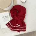 Detailed shot of a cozy red knitted wool scarf with white striped hem on fluffy background. - 160x21cm / Red