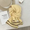 Detail shot of cozy yellow knitted wool scarf with brown stripes and product label. - 160x21cm / Yellow