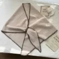 Vue détaillée du châle triangulaire en tricot avec bord contrasté et boucle en cuir. - Flocons d'Avoine