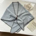Détail châle triangulaire duveteux bleu tricoté, bords contrastés marron et boucle en cuir. - Gris