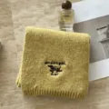 Primer plano detallado de la bufanda de punto amarillo suave con lindo bordado de salchicha. - Amarillo