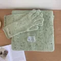Speckled knit green scarf and warm gloves detail, cozy winter wool fabric texture close-up. - Green