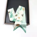 Vue détaillée d'un foulard en soie étroit vert menthe à motif floral blanc pour sac ou cheveux. - 130cmx6cm / Style 04 (Vert Clair Fleur Blanche)