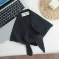 Primer plano detallado del pañuelo triangular de lana negra con textura fina y etiqueta. - Estilo Negro Dos
