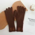Détail en gros plan de gants en tricot de laine marron avec écusson en cuir, chauds et tendance. - Marron