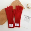 Vue détaillée de gants longs tricotés en laine rouge avec écusson de marque, hiver. - Rouge