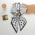 Gedetailleerd uitzicht van een chique zwart-witte polkadot zijden lintscarf met elegante randen. - Wit Stippen