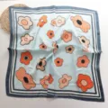 Detailopname van de blauwe sjaal van satijn met oranje bloemmotieven en nette randen. - 68*68cm / Blauw