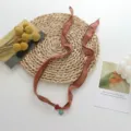 Detailed view of a bohemian fabric ribbon necklace with evil eye pendant and delicate design. - Brown