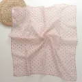 Close-up detail of the pink square scarf featuring delicate red geometric triangle patterns. - Pink