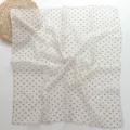 Detail view of soft cotton-linen small square scarf featuring geometric triangle print pattern. - Beige