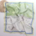 Detailopname van de groen-witte zijden sjaal met een delicaat vlinder- en bloemenprintpatroon. - 70*70cm / Color Block