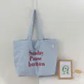 Detailansicht der blau-weiß gestreiften Canvas-Tasche mit rotem Buchstaben-Druck. - Einheitsgröße / Blau
