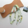 Vue rapprochée de l'élégant foulard en soie à fleurs vertes avec pendentif perle et texture délicate. - 140x3cm / Vert loriot