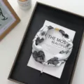 Close-up detail of the elegant black and white floral silk scarf with magnetic buckle. - 51*4cm / Black Patterned