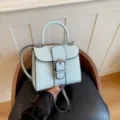 Light blue crocodile pattern handbag with top handle and retro metal buckle closure. - Blue