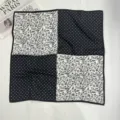 Dettaglio in primo piano di un foulard quadrato nero e bianco chic con motivi floreali e a pois. - Nero/Bianco